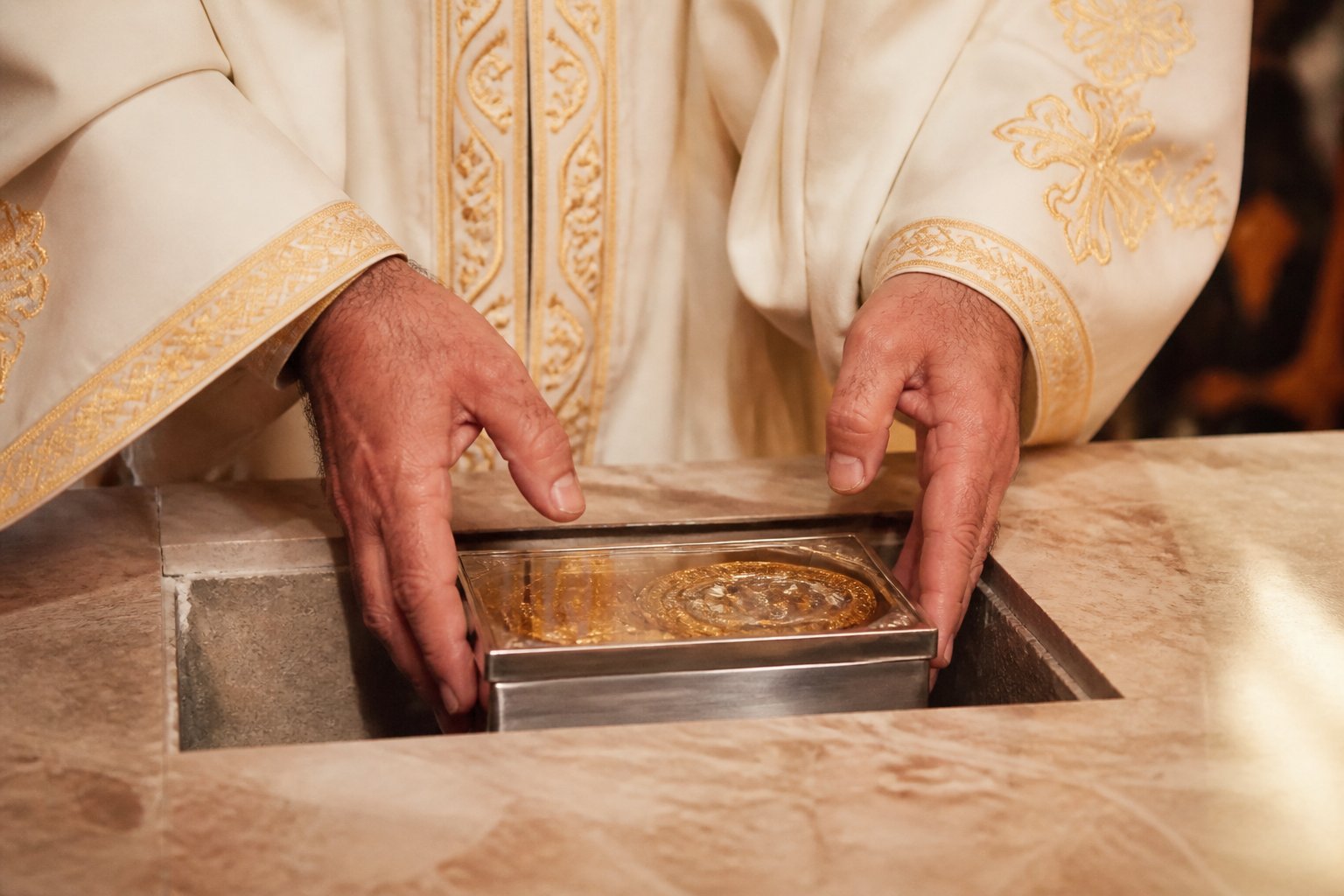 Preot așezând moaște de martiri sub masa sfântă a altarului într-o biserică ortodoxă.